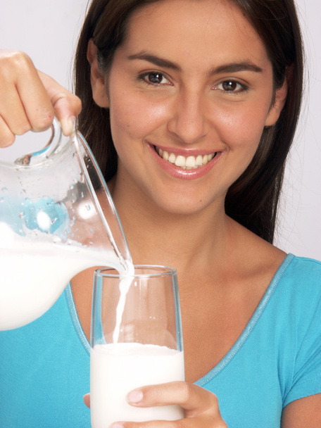 Young woman pouring milk glass. - Zdjęcie, obraz