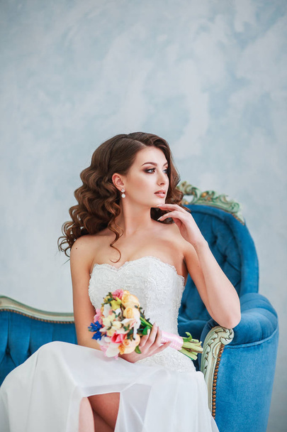 Attractive young woman in a wedding dress. Bride with the bouquet indoor - Fotografie, Obrázek
