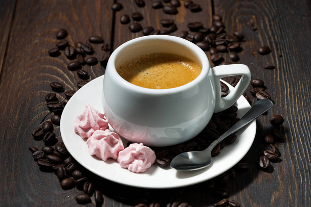 kuppi espressoa ja vaaleanpunaisia marenkeja puupohjalla
 - Valokuva, kuva