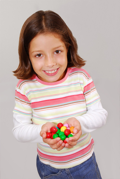 Little girl portrait holding and eating candy. - Φωτογραφία, εικόνα