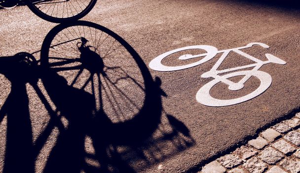 Shadow of unrecognizable cyclist on bicycle lane - Zdjęcie, obraz