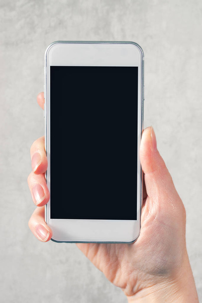 Female hand holding mobile phone with blank mock up screen - Фото, зображення
