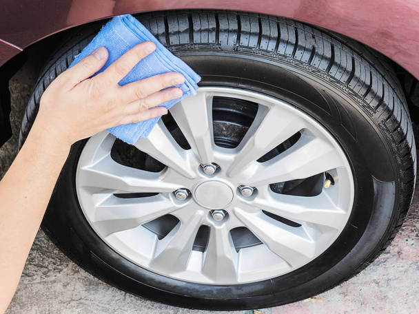 male hand cleaning and waxing tire of car, close-up - Photo, Image