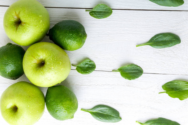 Green fruits on white wooden background. Apple, lime, spinach. Detox. Healthy food. Top view. Copy space. - Foto, immagini