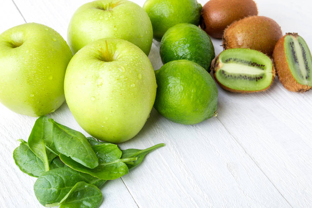 スムージーの材料。白い木製の背景に緑の果実。リンゴ、ライム、ほうれん草、キウイ。デトックス。健康食品. - 写真・画像