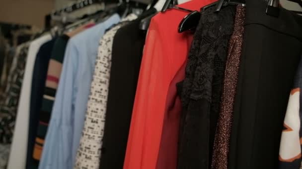 Closeup shooting rack with hangers with different colorful clothes - Footage, Video