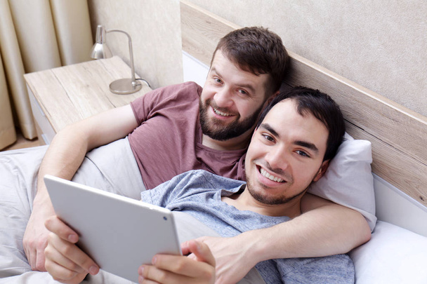 Gay couple lying on bed   - Foto, afbeelding