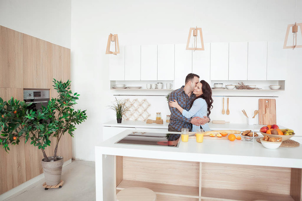 Gelukkige paar knuffelen in de witte loft stile keuken - Foto, afbeelding