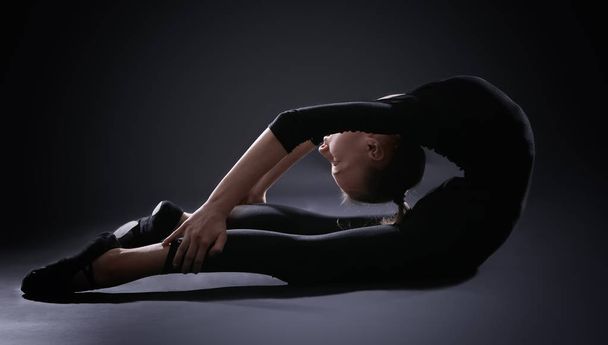 Young girl doing gymnastics on dark background - Фото, зображення