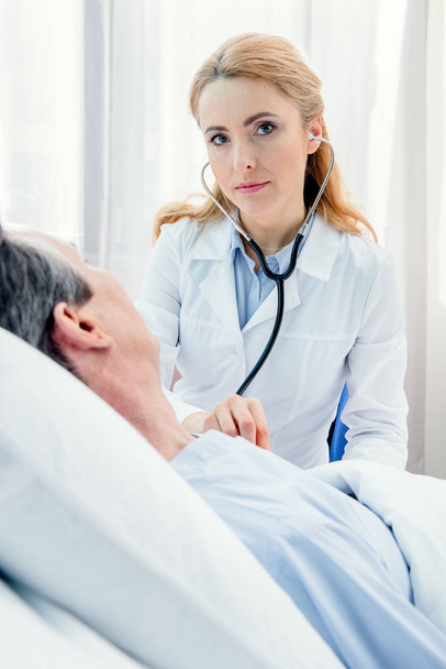 Arts die patiënt met stethoscoop onderzoekt - Foto, afbeelding