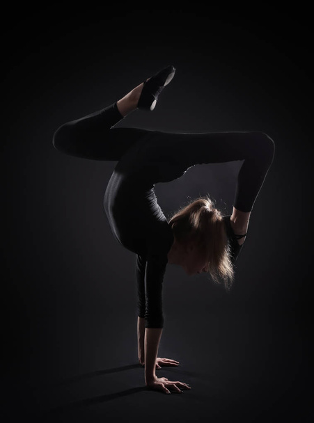 Young girl doing gymnastics on dark background - Zdjęcie, obraz