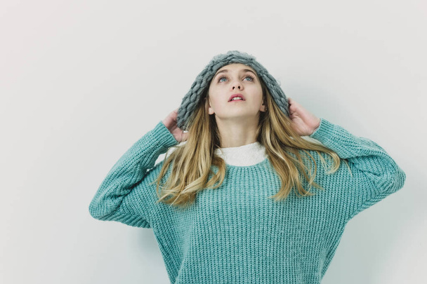 Pretty young girl with blond hair in fashionable sweater, hat - Photo, Image