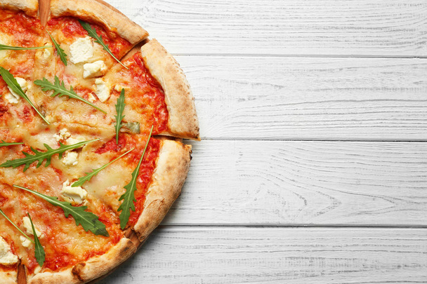Delicious pizza on wooden table - Фото, изображение
