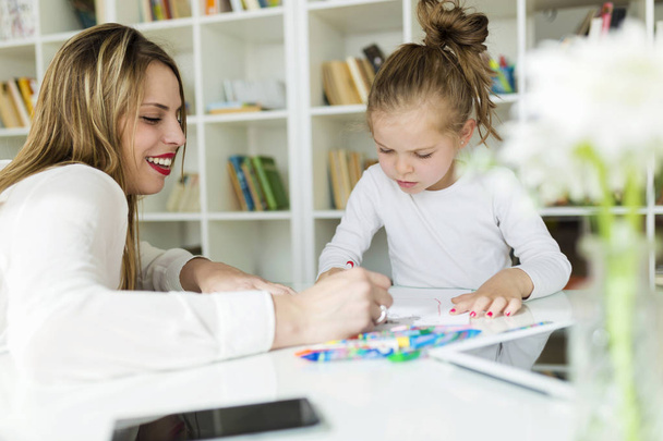 Beautiful mother with her daughter drawing with crayons at home. - Φωτογραφία, εικόνα