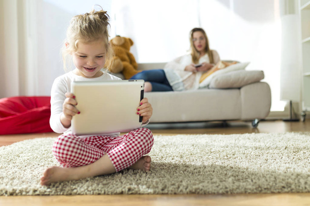Beautiful child playing with digital tablet at home. - Φωτογραφία, εικόνα