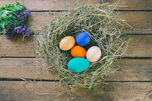 Multi-colored Easter eggs on a wooden background in the nest. - Photo, image