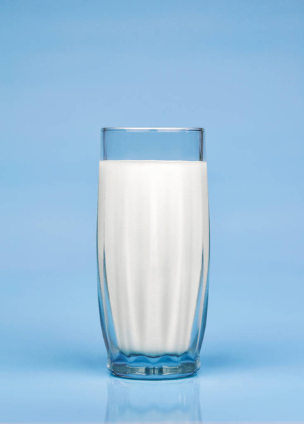Natural whole milk in a glass on blue background.  - 写真・画像