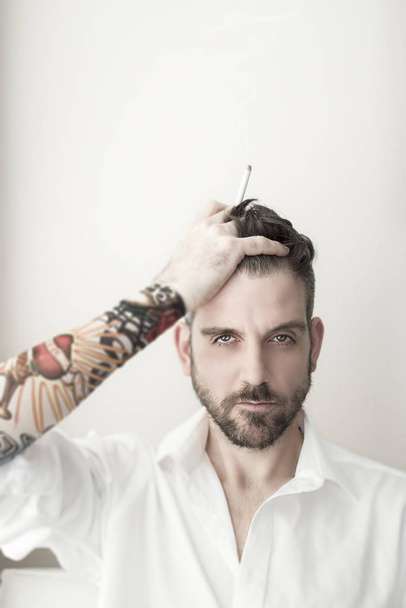 Uomo con tatuaggi e sigaretta in testa
 - Foto, immagini