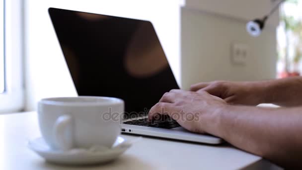 Man working with a laptop in the office and drinking coffee - Filmati, video