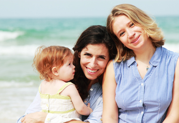 ビーチで赤ちゃんを持つ 2 つの美しい女の子 - 写真・画像