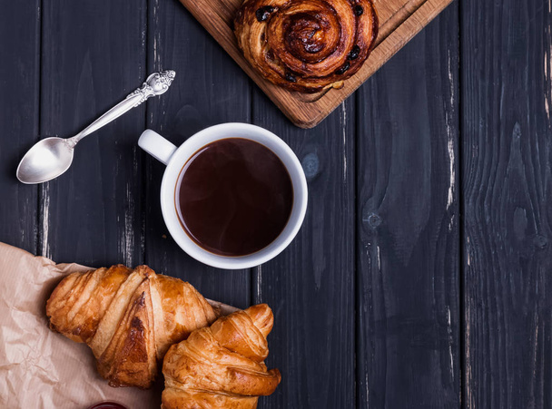 Croissants and coffee in the black wooden table - Foto, Imagen