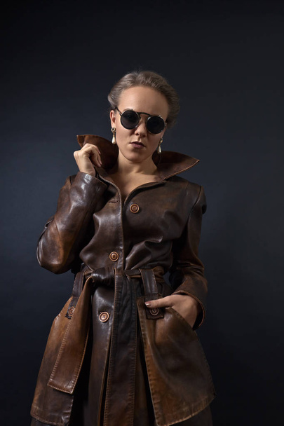 Portrait of young beautiful woman in brown leather coat - Fotó, kép