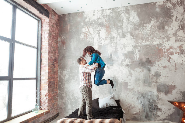 Jong koppel vechten kussens in de loft stijl slaapkamer - Foto, afbeelding