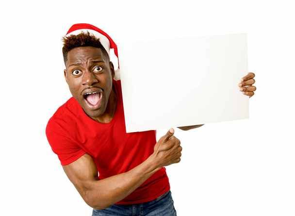 afro american Murzyn w Boże Narodzenie Santa hat uśmiechający się zadowolony, Wyświetlono billboard puste miejsce - Zdjęcie, obraz