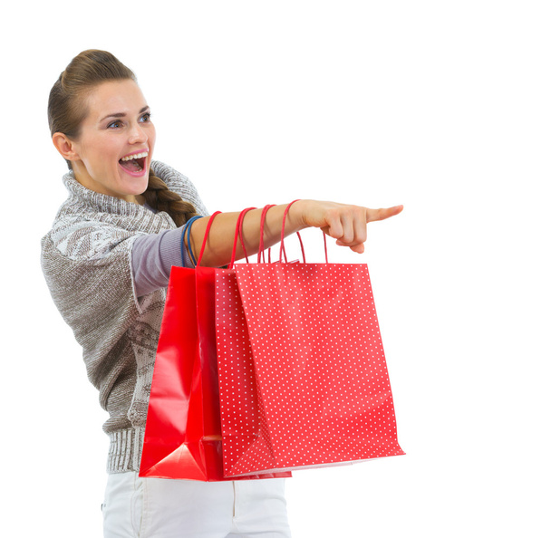 Happy woman in sweater with shopping bags pointing on copy space - Fotoğraf, Görsel