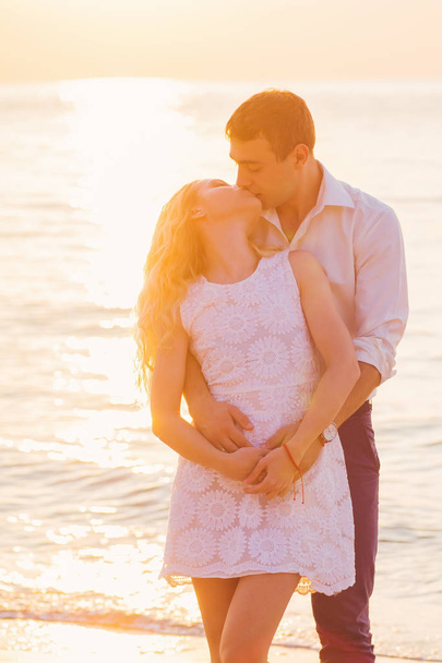 Beautiful young romantic couple kissing on seaside in rays of ri - 写真・画像