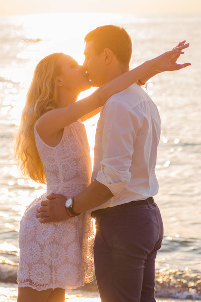 Beautiful young romantic couple kissing on seaside in rays of ri - Фото, зображення