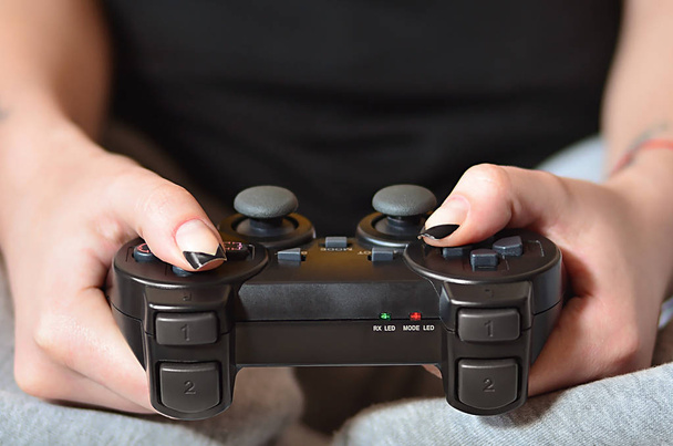 Moderno controlador de juego negro en manos de una joven sentada
 - Foto, imagen