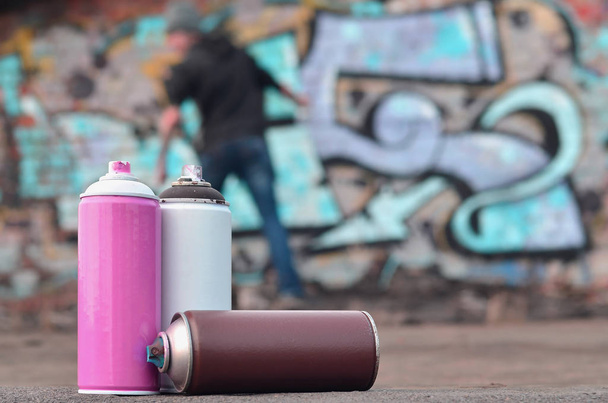 Uma vida-morta de várias latas de tinta usadas de cores diferentes contra a parede, em que um jovem está aplicando graffiti-desenho. Conceito de arte de rua e cultura da arte juvenil para pintar as paredes
 - Foto, Imagem