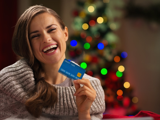 Smiling woman in front of Christmas tree holding credit card - Foto, afbeelding