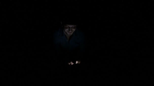Man alone in the dark texting on smartphone illustrating concept of technology slaves - Video, Çekim
