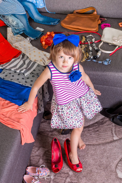 Little girl  wearing  big mother red shoes and bag.  New clothes. Choosing. - Foto, Imagem