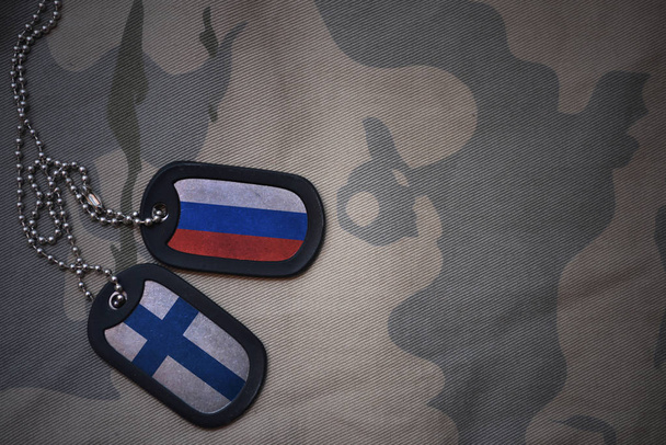 Army blank, dog tag with flag of russia and finland on the khaki texture background. военная концепция
 - Фото, изображение