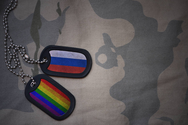 Armee leer, Hundeanhänger mit russischer Flagge und homosexueller Regenbogenfahne auf khakifarbenem Hintergrund. Militärisches Konzept - Foto, Bild