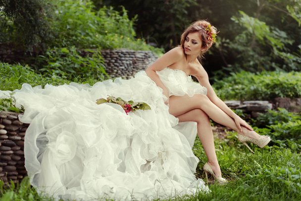 bride woman with long legs in lush wedding dress sits on nature. - Foto, Imagem