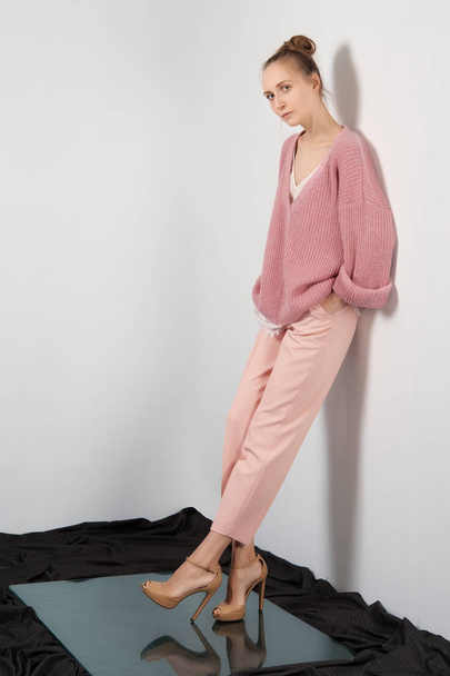 Pretty girl in thin angora sweater and slim pants posing near the wall - Foto, Imagen