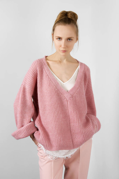 Pretty girl in thin angora sweater and slim pants posing near the wall - Foto, imagen