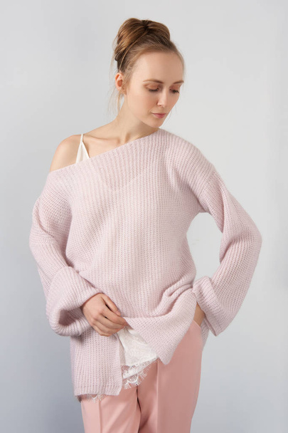 Pretty girl in thin angora sweater and slim pants posing near the wall - Foto, afbeelding