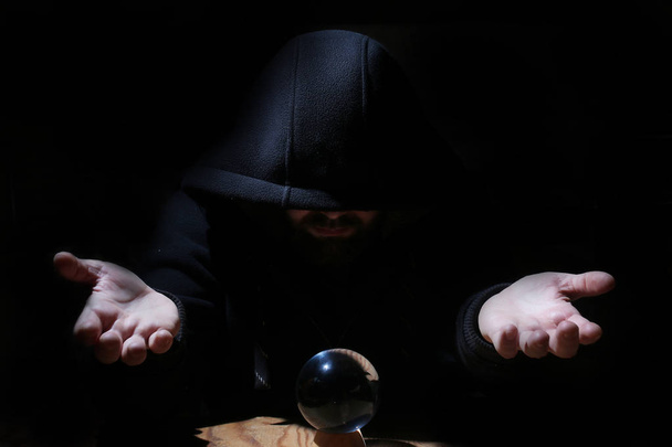 людина в чорному капюшоні з кришталевим м'ячем
 - Фото, зображення