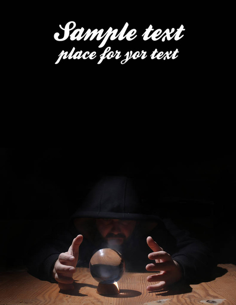 uomo in cappuccio nero con sfera di cristallo e spazio vuoto per il testo
 - Foto, immagini