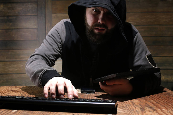 hacker nel cappuccio nero in una stanza con pareti in legno
 - Foto, immagini