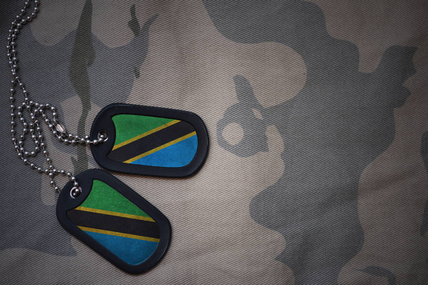 Armee leer, Hundeanhänger mit Flagge von Tansania auf dem khakifarbenen Hintergrund. Militärisches Konzept - Foto, Bild