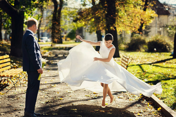 Bride spreads her dress while dancing in the park  - Foto, Imagem