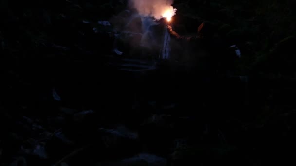 Muž signály pro pomoc s odlesk poblíž vodopád - Záběry, video