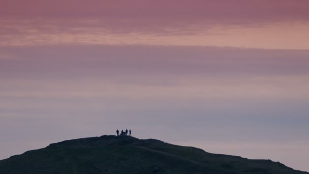 Groep mensen op heuveltop bij zonsondergang - Video