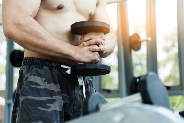 Muscular man lifting dumbbells in gym. copy space. - Photo, image